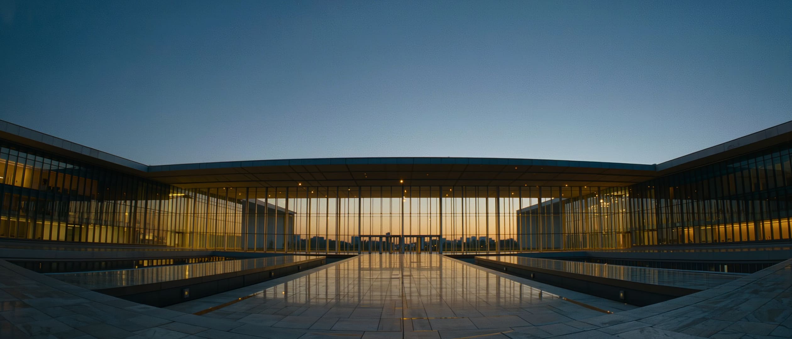 Glass atrium of a modern conference centre glowing at blue hour